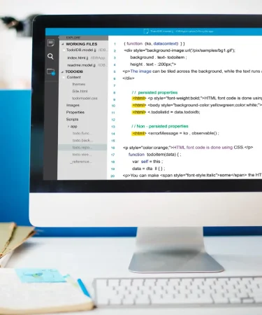 Imagem de um computador exibindo código HTML em uma tela, ilustrando a importância de textos alt text em imagens para acessibilidade e SEO.
