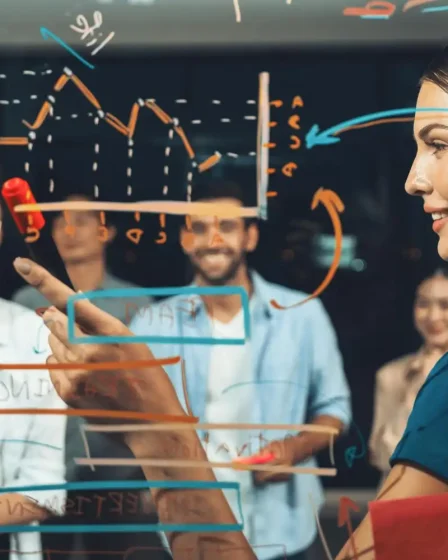 Profissional explicando a estratégia de diversificação de portfólio e o momento ideal para lançar novos produtos na indústria, com colegas atentos ao fundo.